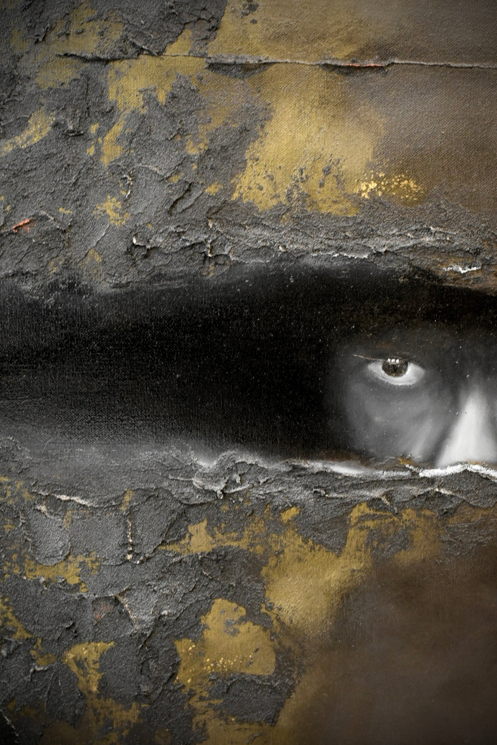 Abstract textured artwork with a dark horizontal band across the center and a partially visible human eye on the right side, set against cracked black, gray, and gold surfaces.
