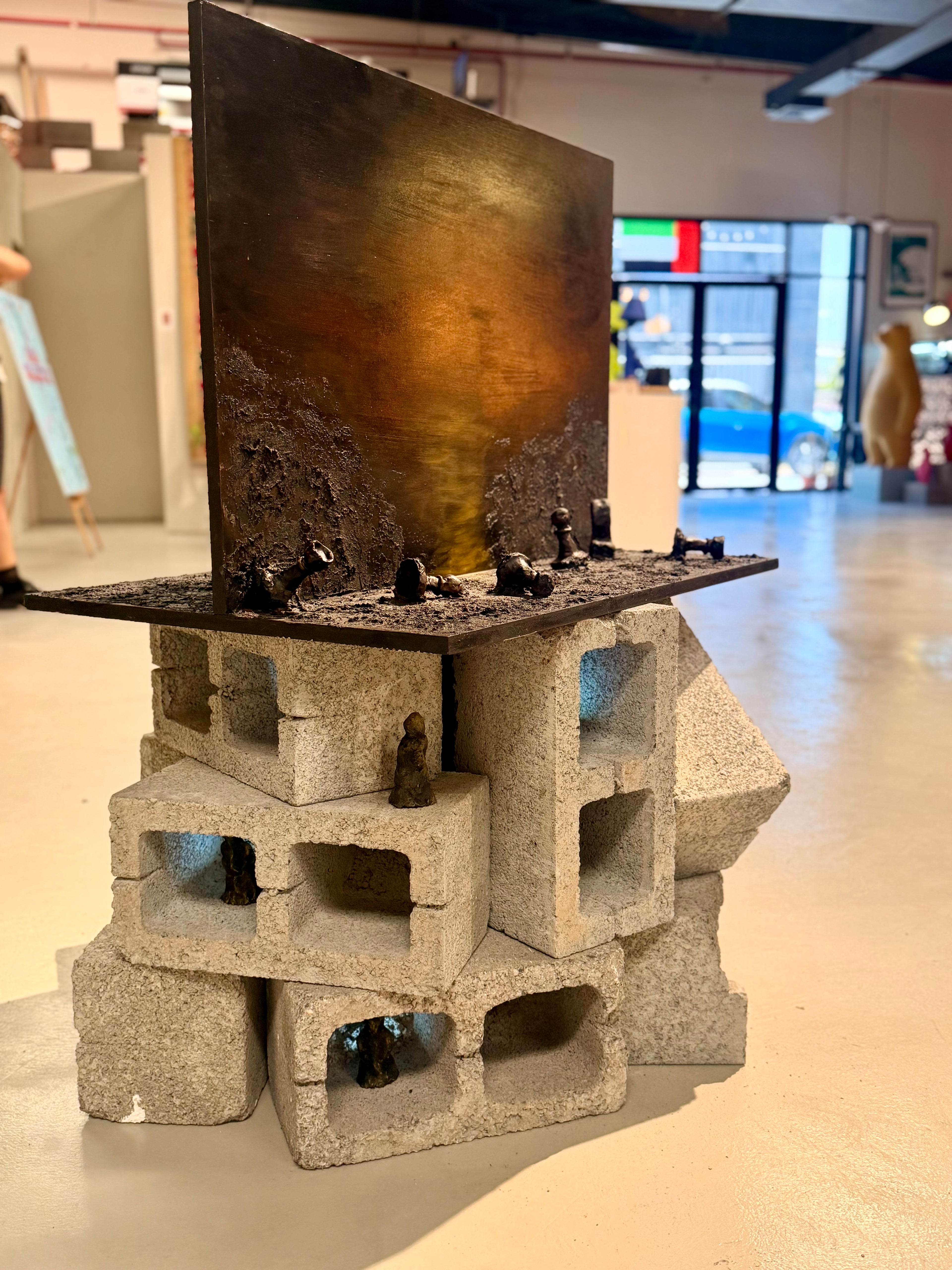 Beyond the Game, contemporary mixed media installation by Cristina Gabriela Buzatu featuring a textured painted landscape, sculptural chess pieces, terracotta human figures and architectural concrete blocks exploring power and human consequence.