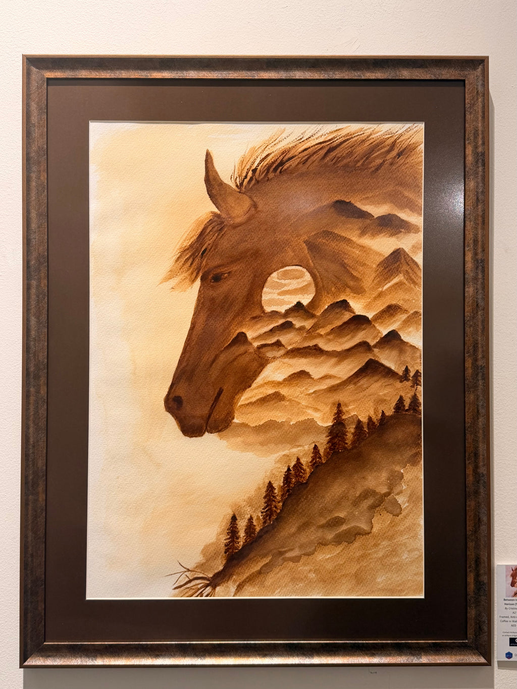 Coffee painting on paper by Cristina Gabriela Buzatu depicting a horse whose silhouette contains mountains, forests and a distant landscape, framed with matte anti-glare glass.