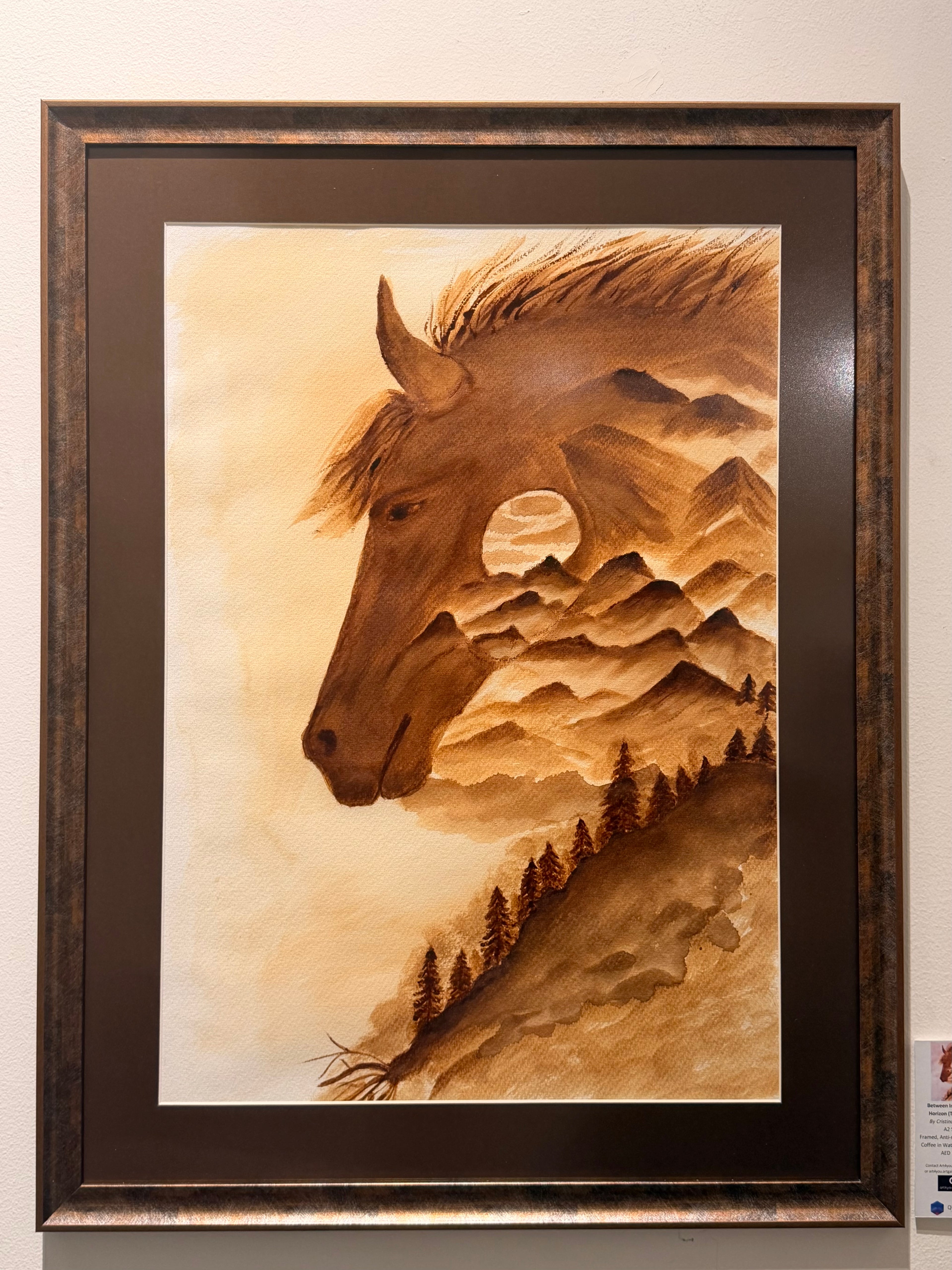 Coffee painting on paper by Cristina Gabriela Buzatu depicting a horse whose silhouette contains mountains, forests and a distant landscape, framed with matte anti-glare glass.
